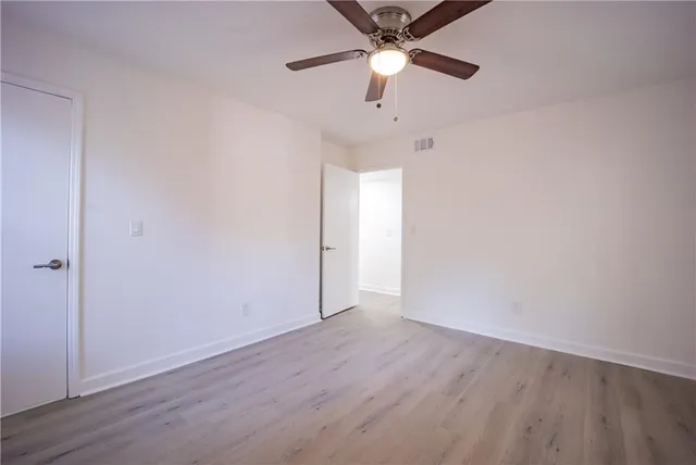 an empty room with wooden floor and ceiling fan