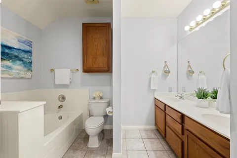 a spacious bathroom with a granite countertop sink a toilet a mirror and shower