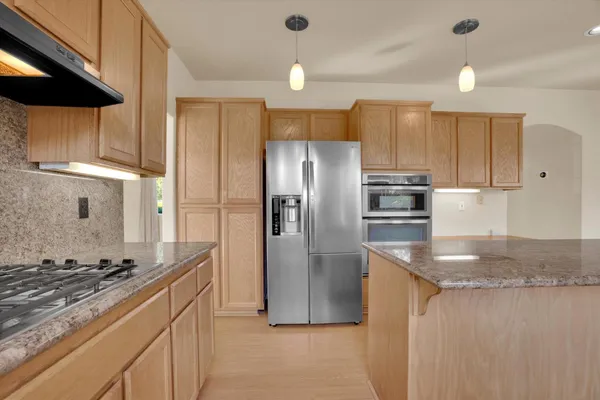 a kitchen with stainless steel appliances granite countertop a refrigerator a sink and a stove