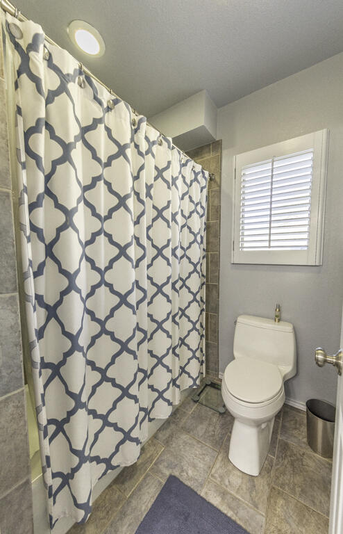 3620 93rd Street Lubbock, TX 79423 - Photo 18 of 33 a bathroom with a toilet and a shower curtain