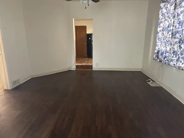 an empty room with wooden floor windows and closet