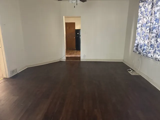 an empty room with wooden floor windows and closet