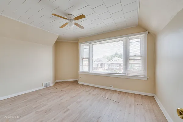 an empty room with wooden floor fan and windows
