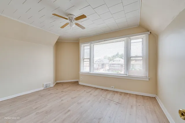 an empty room with wooden floor fan and windows