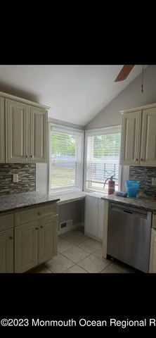 a kitchen with granite countertop a stove a sink a window and wooden cabinets