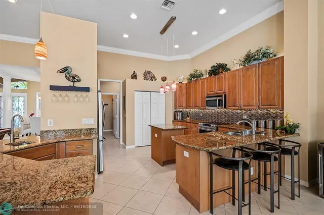 a kitchen with kitchen island granite countertop a sink counter top space appliances and cabinets