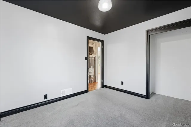 a view of empty room with wooden floor and kitchen