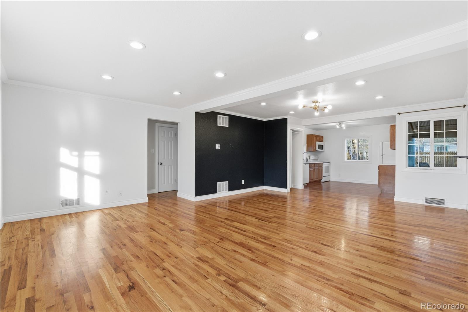860 Lansing Street Aurora, CO 80010 - Photo 4 of 31 a view of an empty room with wooden floor and a kitchen