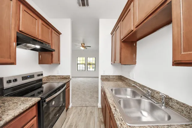 a kitchen with granite countertop a sink a stove and cabinets