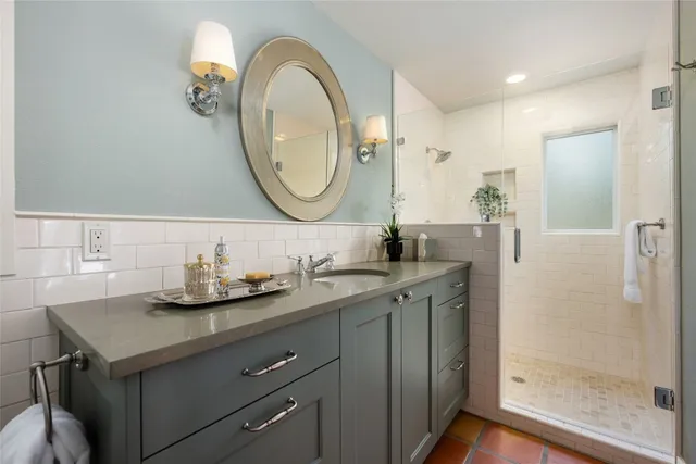 a bathroom with a granite countertop sink a mirror and a shower