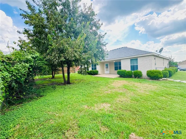 a view of a house next to a big yard and large trees