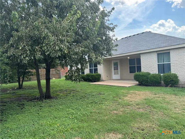 a view of a house with backyard and a tree