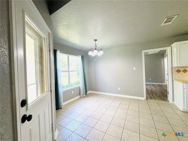 a view of an empty room with window and chandelier fan