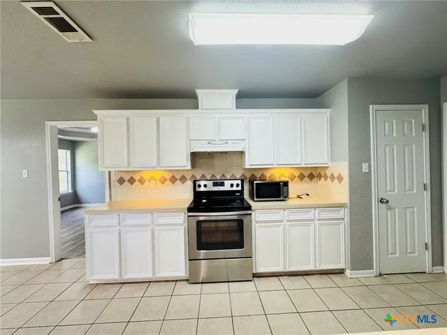a kitchen with granite countertop white cabinets and stainless steel appliances