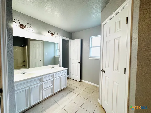 a spacious bathroom with a shower a sink and a mirror