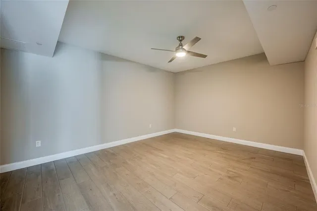 an empty room with a window and ceiling fan