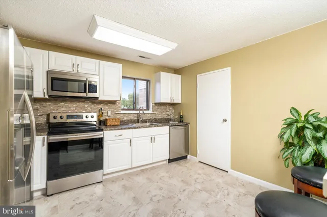a kitchen with granite countertop a stove a sink and a microwave