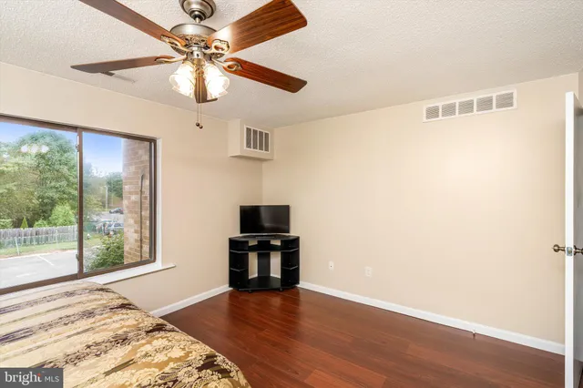a view of empty room with wooden floor and fan