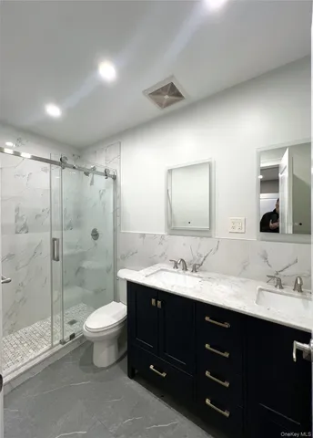 a bathroom with a double vanity sink toilet mirror and shower