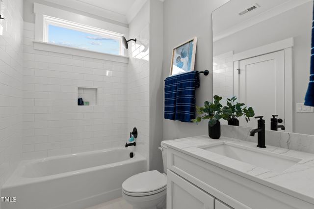 a bathroom with a granite countertop bathtub sink vanity mirror and toilet