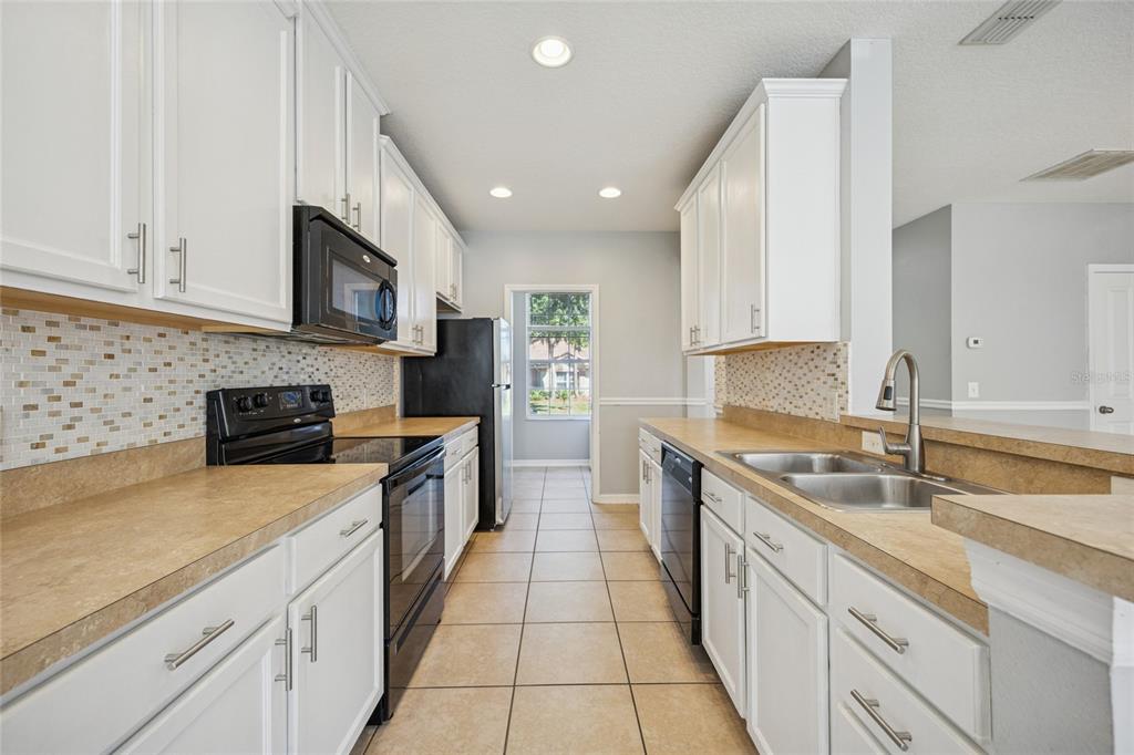 3140 Riachuelo Lane Kissimmee, FL 34744 - Photo 7 of 24 a large kitchen with stainless steel appliances granite countertop a sink a stove top oven and white cabinets