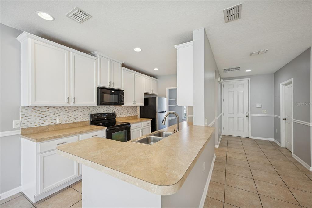 3140 Riachuelo Lane Kissimmee, FL 34744 - Photo 8 of 24 a kitchen with stainless steel appliances a microwave a sink a stove a microwave and island
