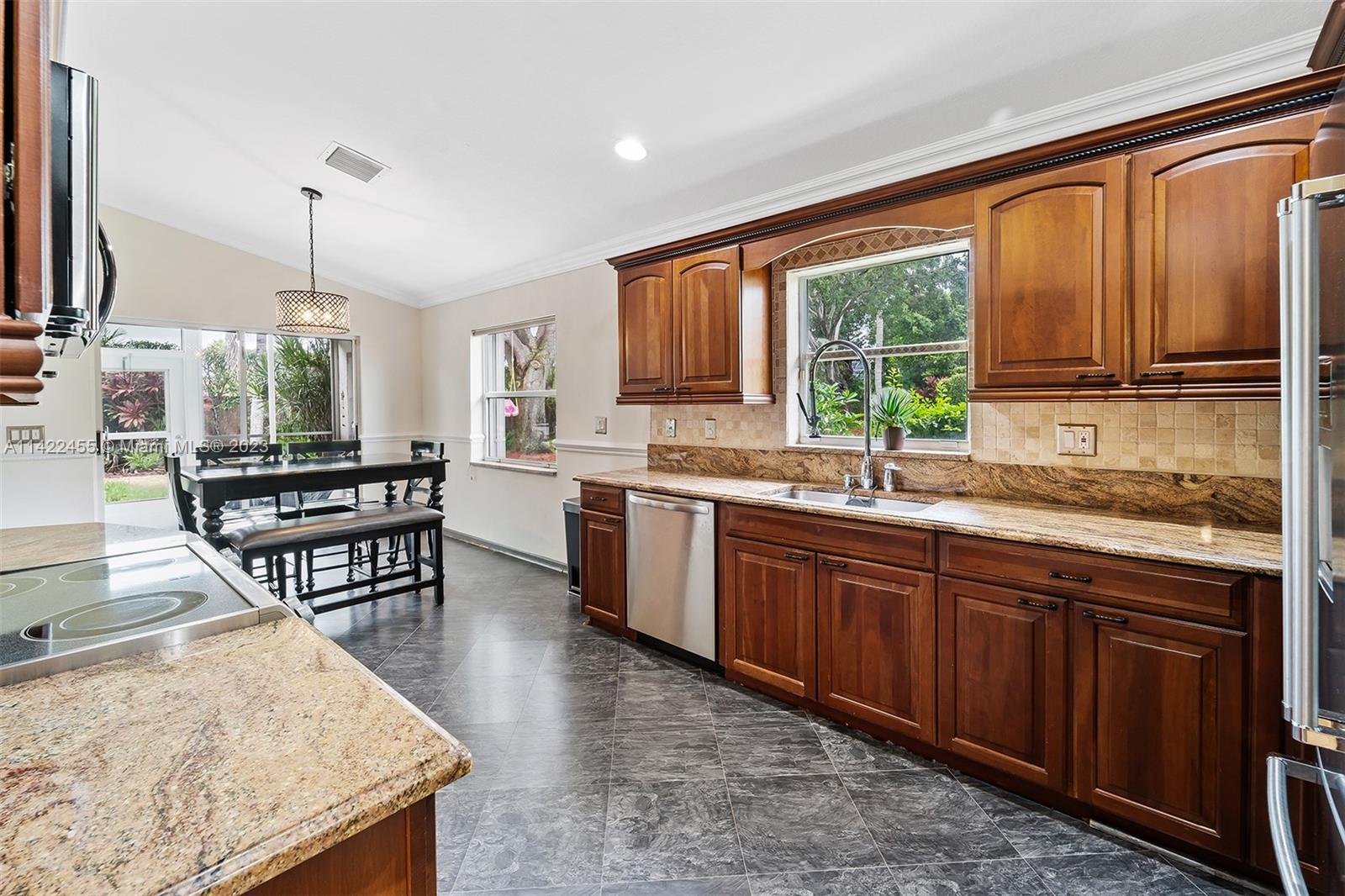 22699 Royal Crown Terrace East Boca Raton, FL 33433 - Photo 17 of 36 a open kitchen with granite countertop a stove a sink dishwasher a dining table and chairs with wooden floor
