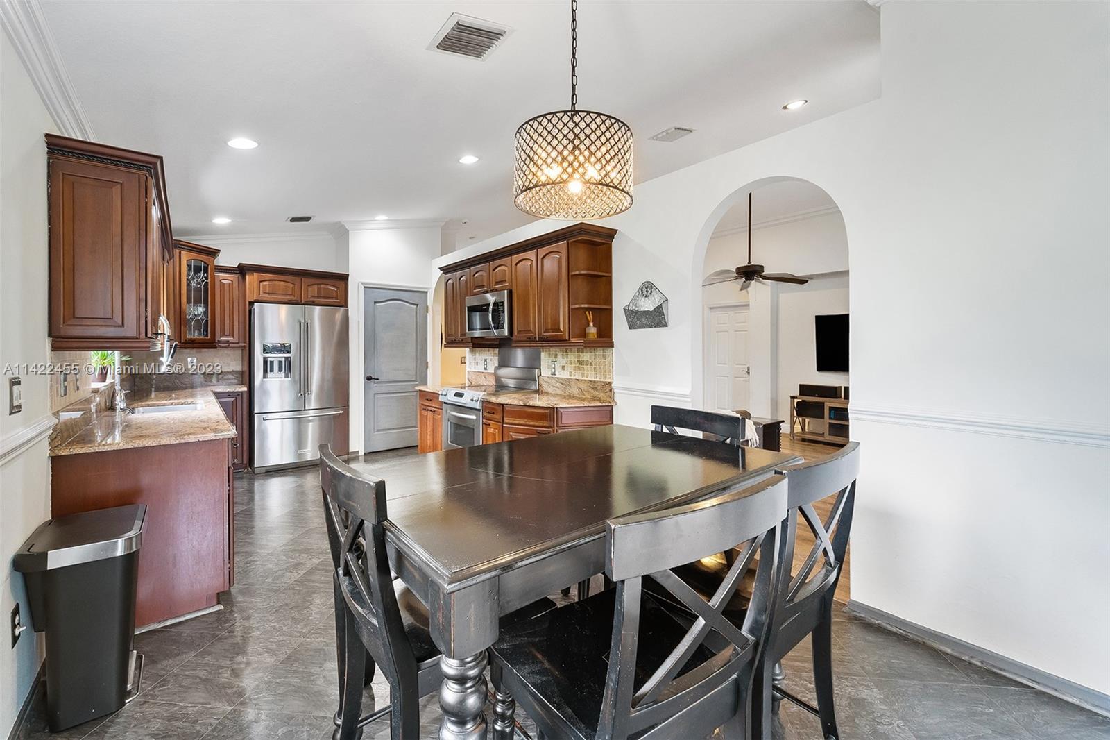 22699 Royal Crown Terrace East Boca Raton, FL 33433 - Photo 18 of 36 a kitchen with stainless steel appliances granite countertop a stove a refrigerator a kitchen island a table and chairs with wooden floor