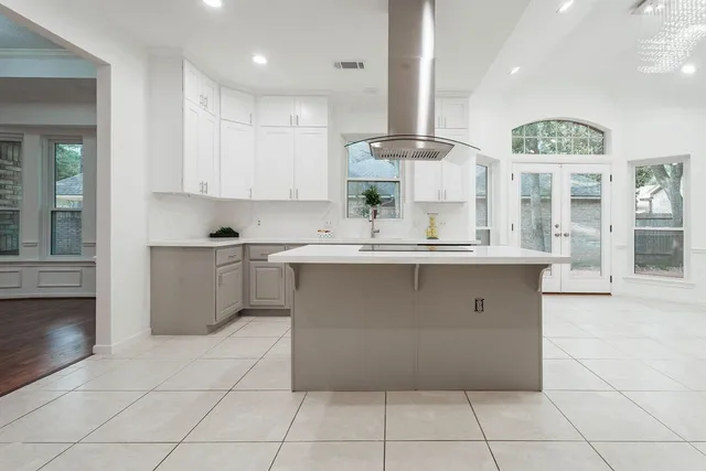 a large white kitchen with a large window and stainless steel appliances