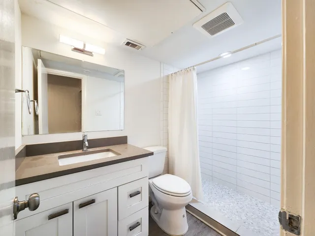 a bathroom with a granite countertop sink toilet and shower
