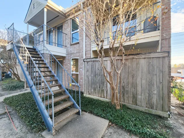 a view of a wooden house with a small yard and wooden fence