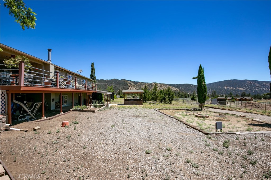 10960 Steinhoff Road Frazier Park, CA 93225 - Photo 17 of 46 Ground-level view of the home's side profile, featuring an upper-level balcony deck, wide open side yard, and a beautiful mountain backdrop.
