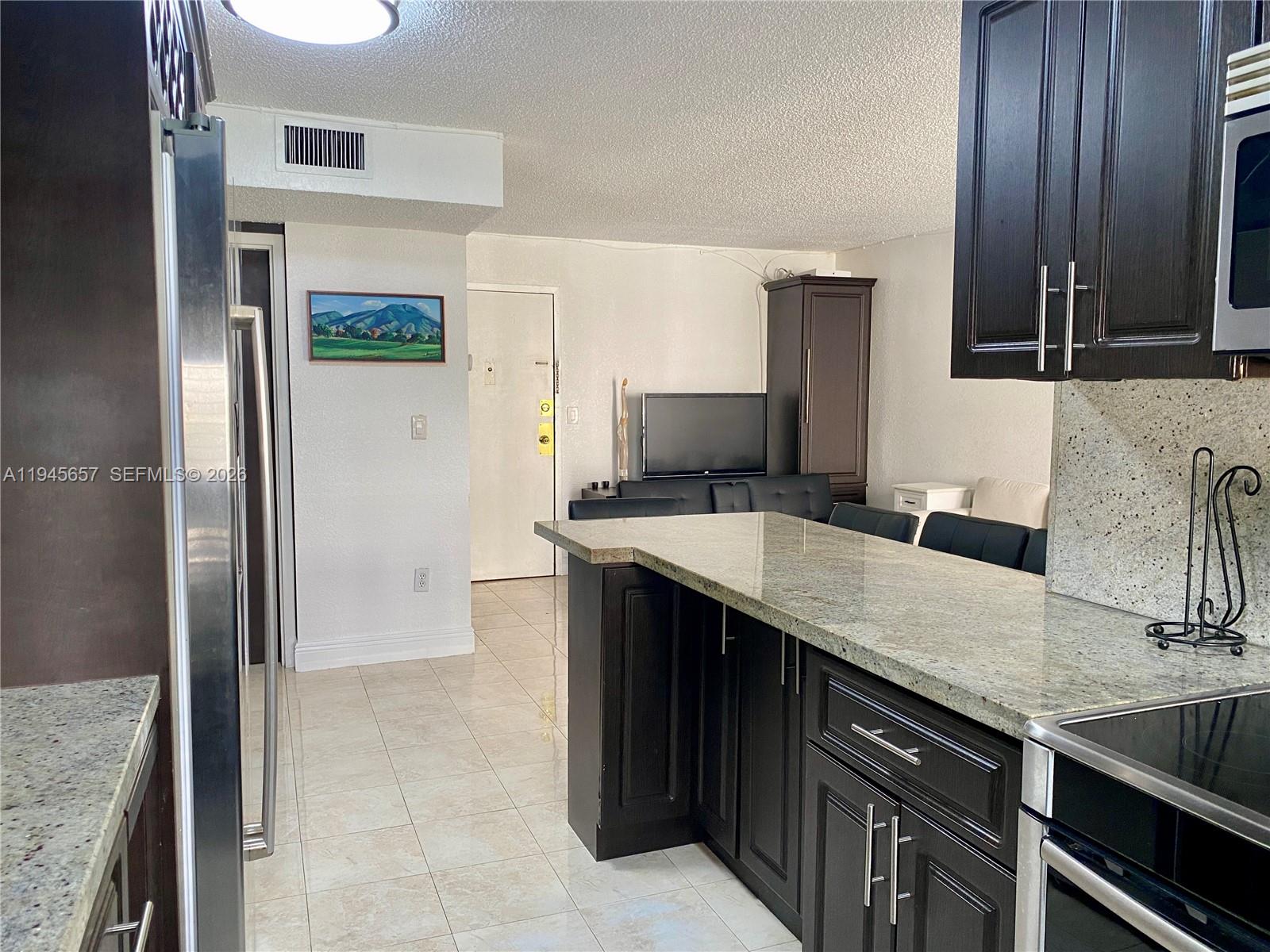 17011 North Bay Road, Unit 304 Sunny Isles Beach, FL 33160 - Photo 12 of 54 a kitchen with stainless steel appliances granite countertop a sink and a refrigerator