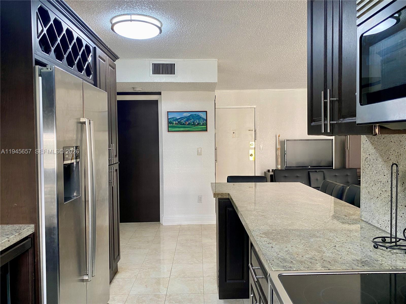 17011 North Bay Road, Unit 304 Sunny Isles Beach, FL 33160 - Photo 13 of 54 a kitchen with stainless steel appliances granite countertop a refrigerator and a stove
