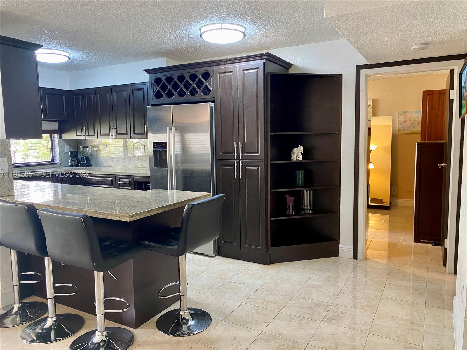 17011 North Bay Road, Unit 304 Sunny Isles Beach, FL 33160 - Photo 27 of 54 a kitchen with granite countertop a refrigerator and a stove top oven