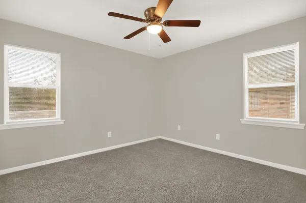 an empty room with a window and a fan