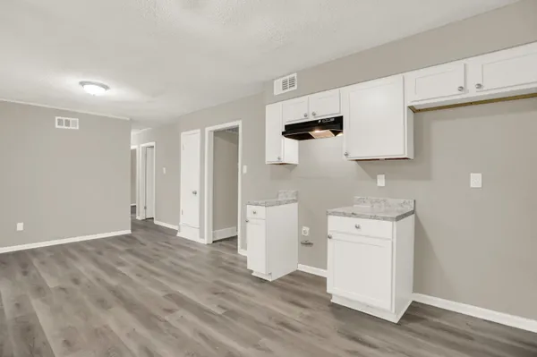 a view of a kitchen with white cabinets and wooden floor