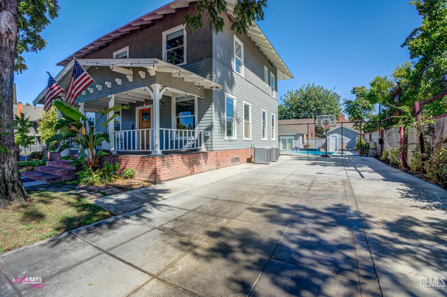 Undisclosed Address Bakersfield, CA 93301 - Photo 7 of 58 a view of a white house with many windows plants and large tree