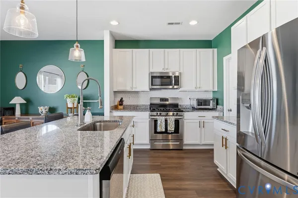 a kitchen with stainless steel appliances granite countertop a sink refrigerator and microwave