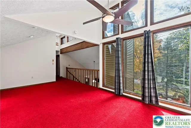 an empty room with windows and fan