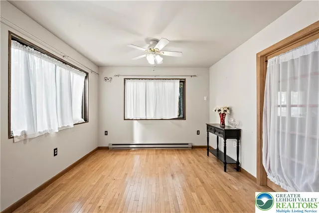 an empty room with windows and chandelier fan