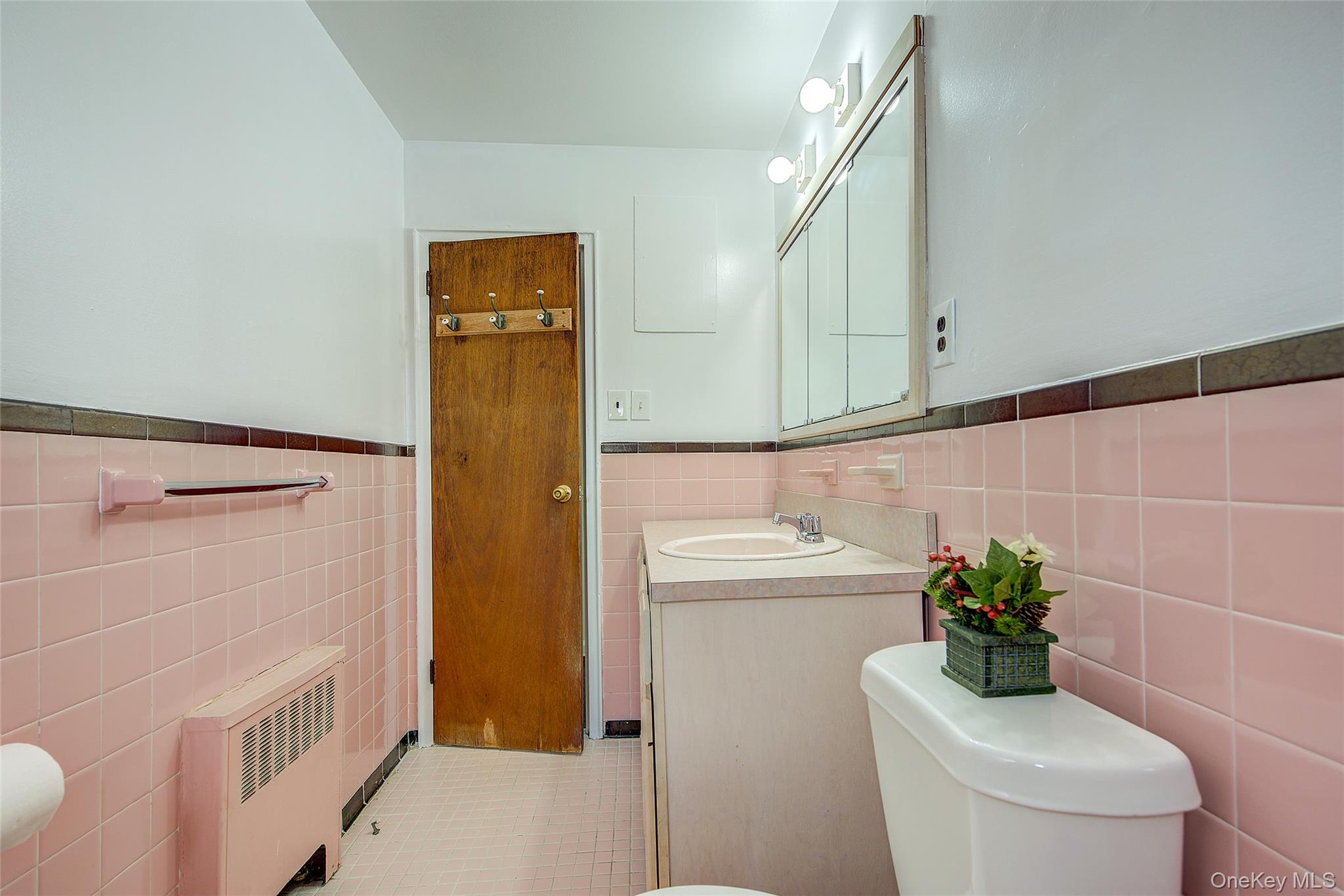163-02 45th Avenue Queens, NY 11358 - Photo 12 of 35 Half bath featuring a wainscoted wall, tile walls, radiator heating unit, vanity, and light tile patterned floors