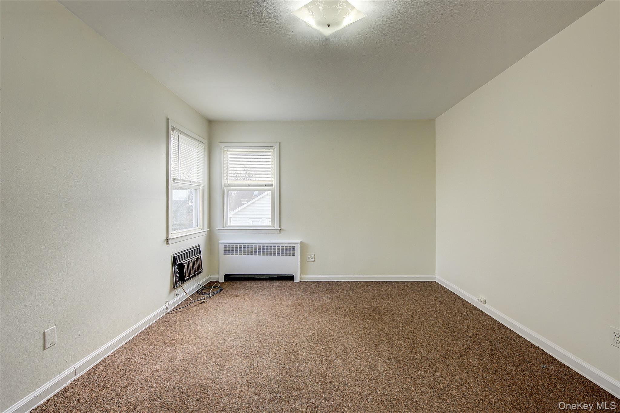 163-02 45th Avenue Queens, NY 11358 - Photo 18 of 35 Spare room featuring radiator heating unit, carpet flooring, and heating unit