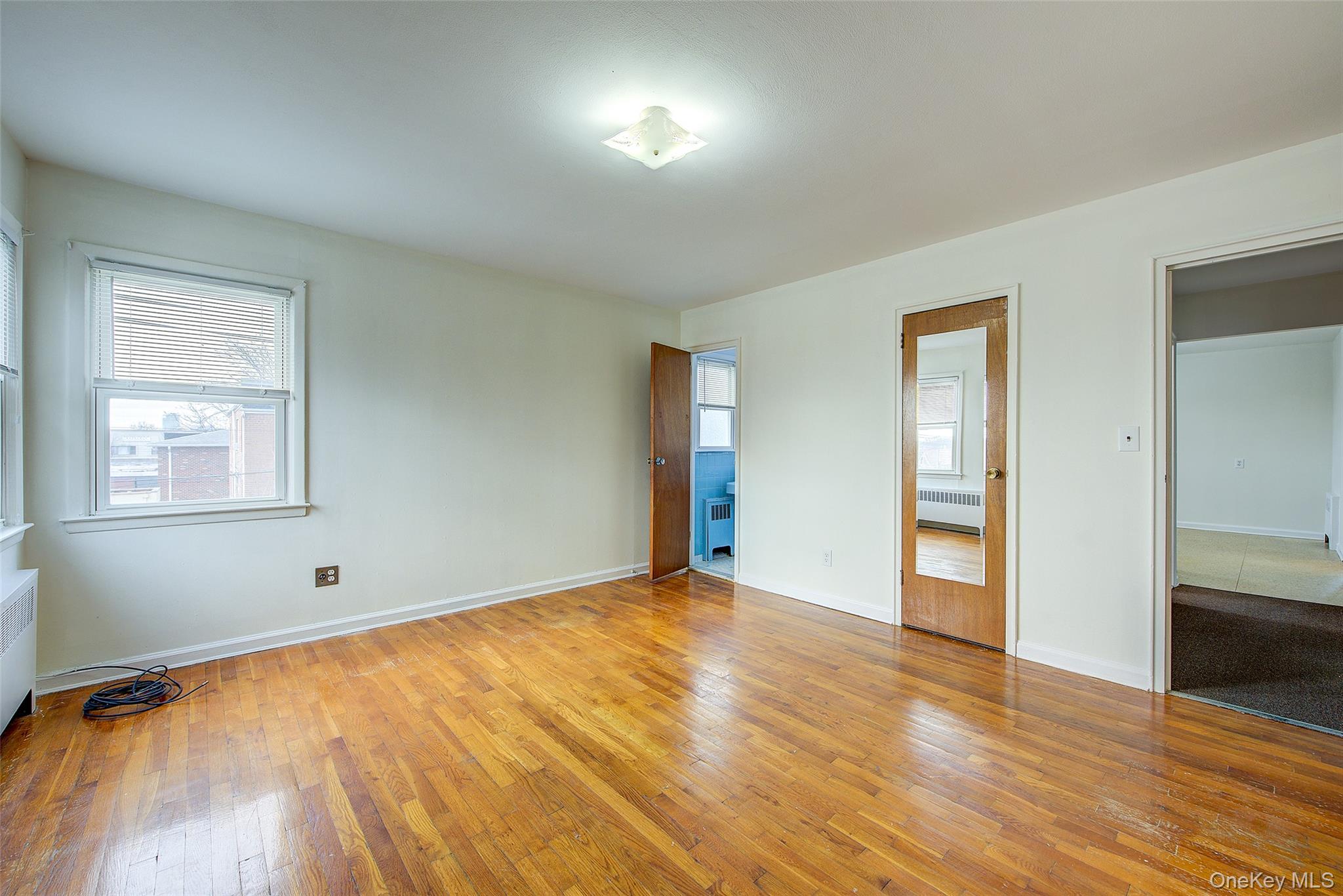 163-02 45th Avenue Queens, NY 11358 - Photo 21 of 35 Unfurnished bedroom with light wood finished floors and radiator heating unit