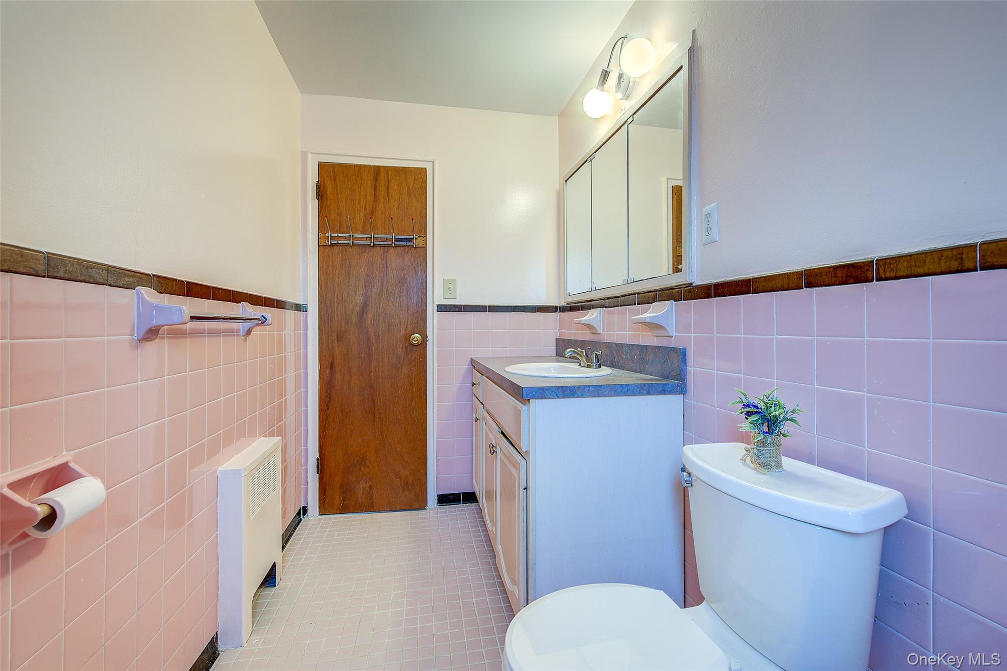163-02 45th Avenue Queens, NY 11358 - Photo 25 of 35 Half bath featuring vanity, wainscoting, radiator, tile walls, and light tile patterned floors