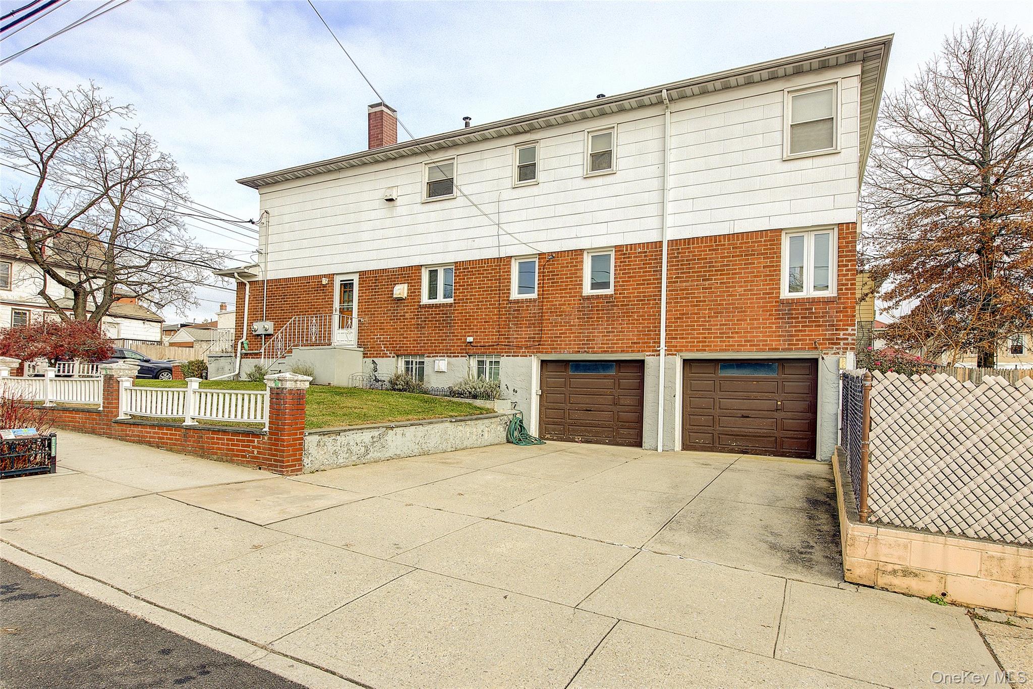 163-02 45th Avenue Queens, NY 11358 - Photo 33 of 35 Back of property featuring a fenced front yard, concrete driveway, a chimney, and a garage
