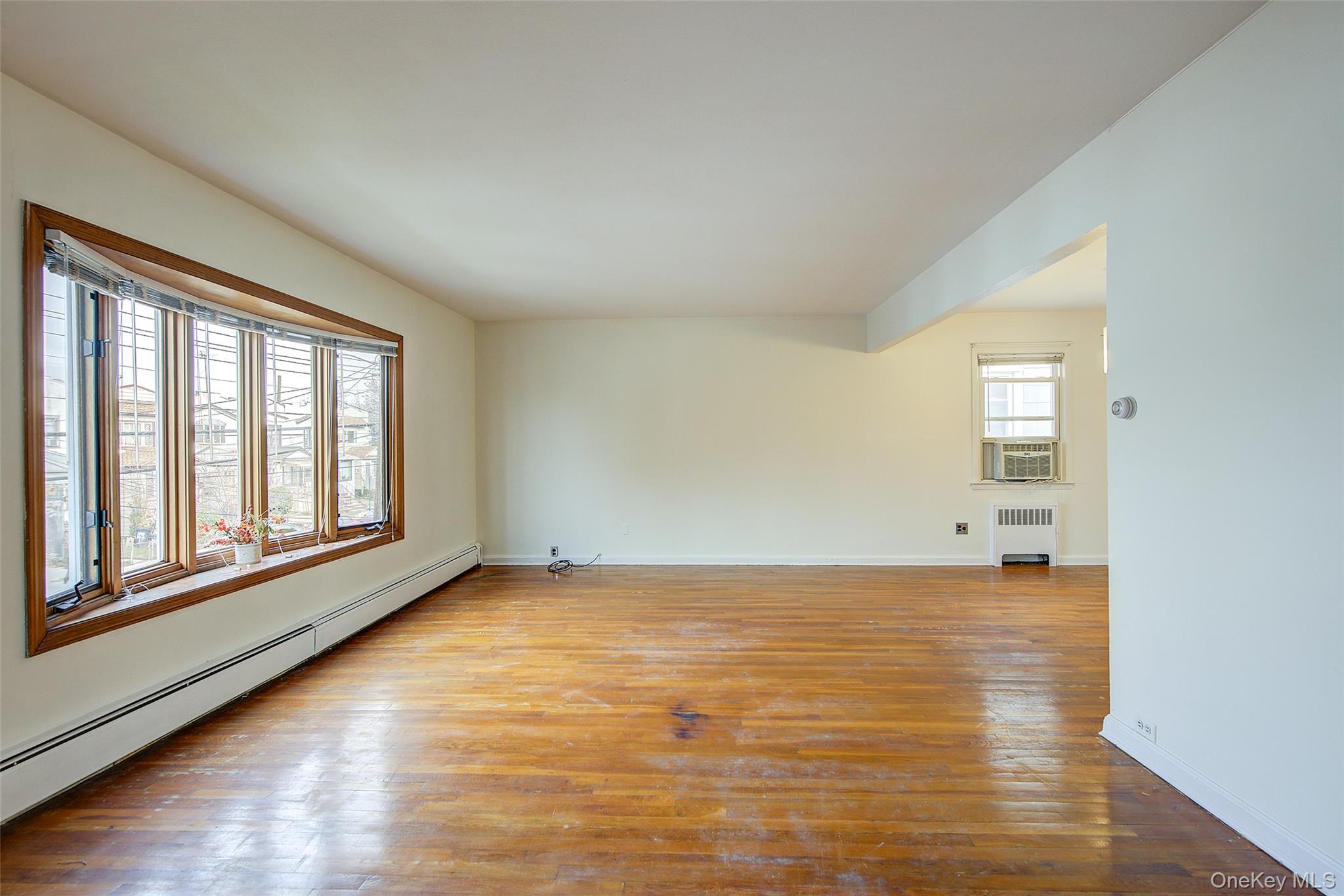 163-02 45th Avenue Queens, NY 11358 - Photo 7 of 35 Unfurnished room featuring a baseboard heating unit, hardwood / wood-style floors, radiator, and cooling unit