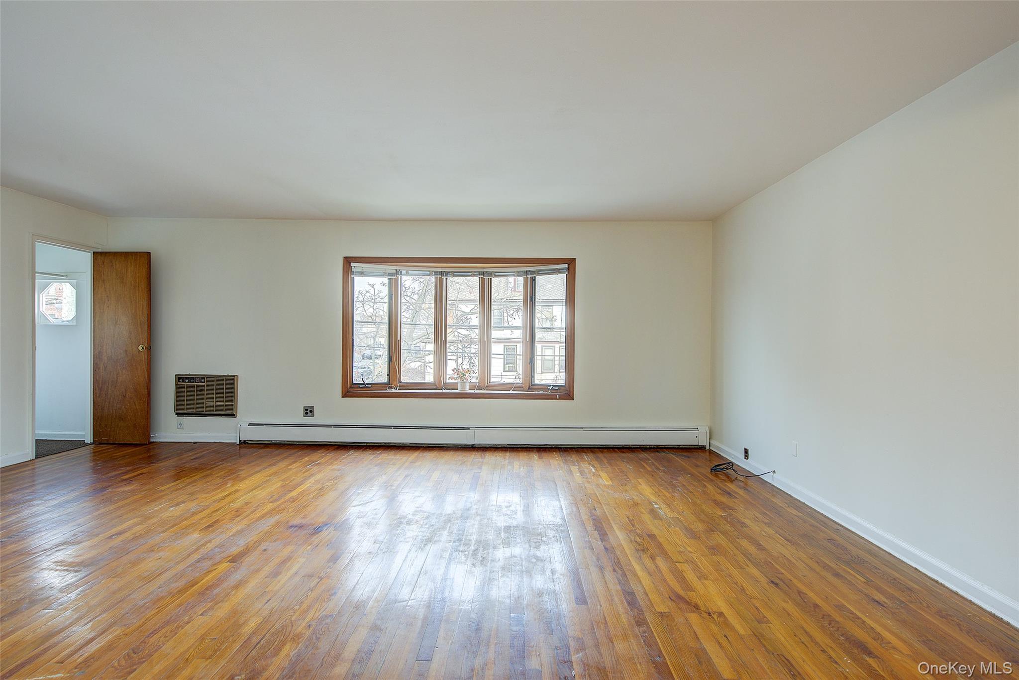 163-02 45th Avenue Queens, NY 11358 - Photo 8 of 35 Unfurnished living room with hardwood / wood-style floors and a baseboard radiator
