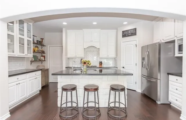 a kitchen with stainless steel appliances granite countertop a refrigerator and a stove top oven