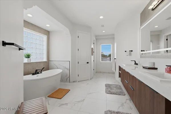 a spacious bathroom with a double vanity sink a mirror and a bathtub